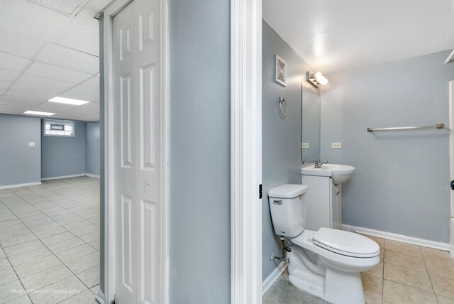 bathroom with tile patterned flooring, vanity, toilet, and a drop ceiling