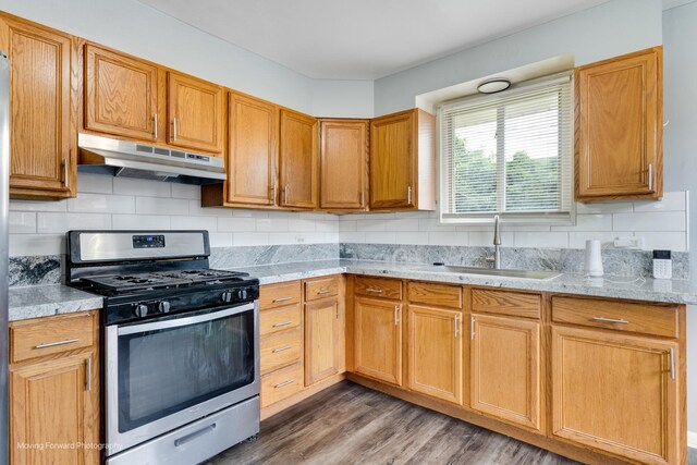 kitchen with light stone countertops, hardwood / wood-style floors, sink, decorative backsplash, and stainless steel gas stove