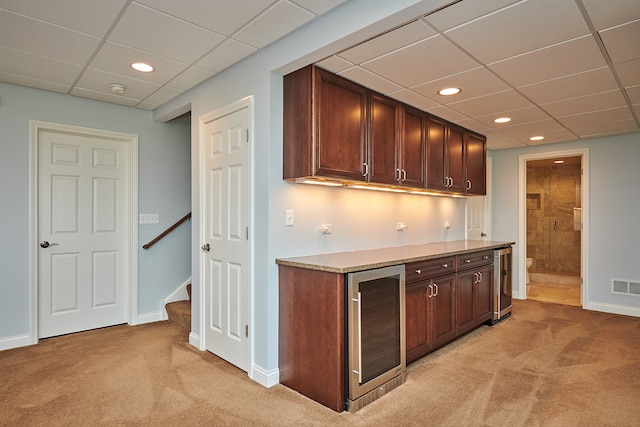 bar with a paneled ceiling, beverage cooler, light carpet, and dark brown cabinetry