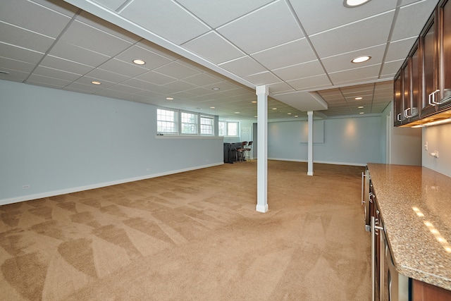 basement featuring a paneled ceiling and light colored carpet