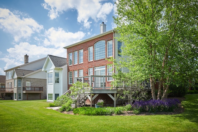 rear view of house with a lawn and a wooden deck