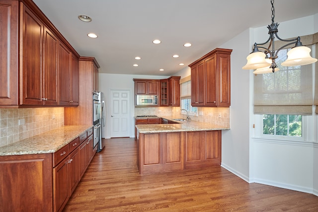 kitchen with appliances with stainless steel finishes, kitchen peninsula, and light hardwood / wood-style flooring