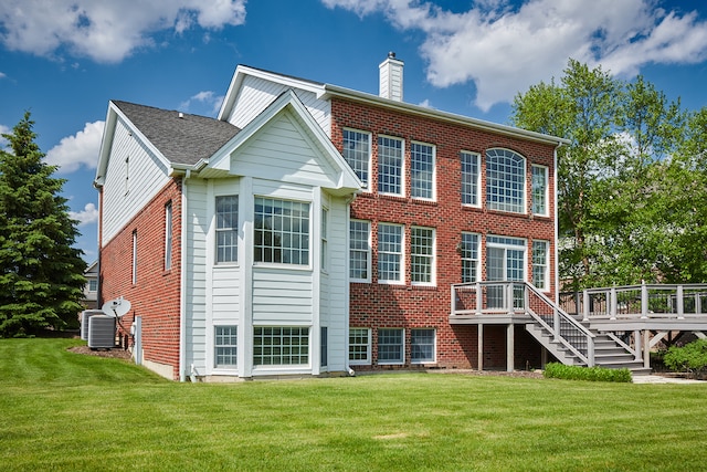 rear view of property with central air condition unit, a wooden deck, and a lawn