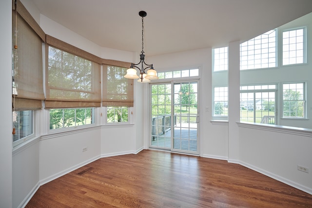 unfurnished dining area with hardwood / wood-style floors and an inviting chandelier