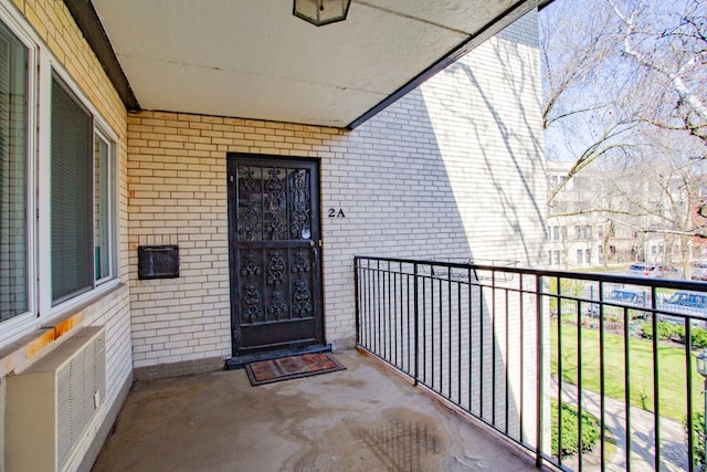 view of exterior entry featuring a balcony and a wall mounted air conditioner