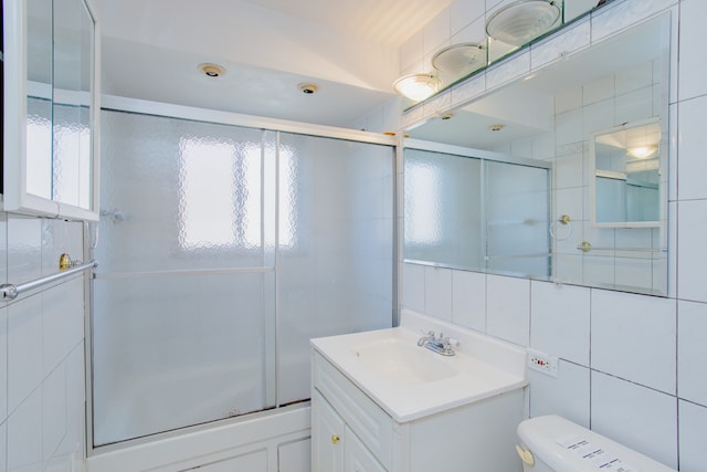 bathroom featuring vanity, tile walls, and toilet