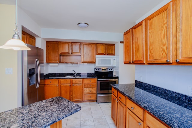 kitchen featuring dark stone counters, light tile patterned floors, stainless steel appliances, sink, and hanging light fixtures