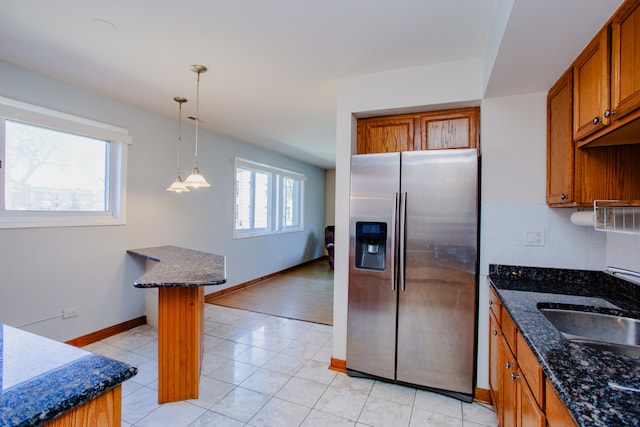 kitchen with dark stone countertops, stainless steel fridge, decorative backsplash, and light hardwood / wood-style floors