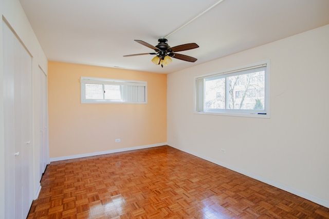 interior space featuring multiple windows, ceiling fan, and light parquet floors