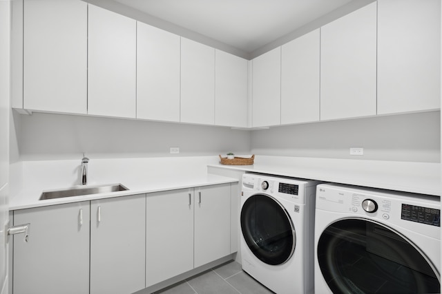 clothes washing area with cabinets, light tile patterned floors, washing machine and dryer, and sink