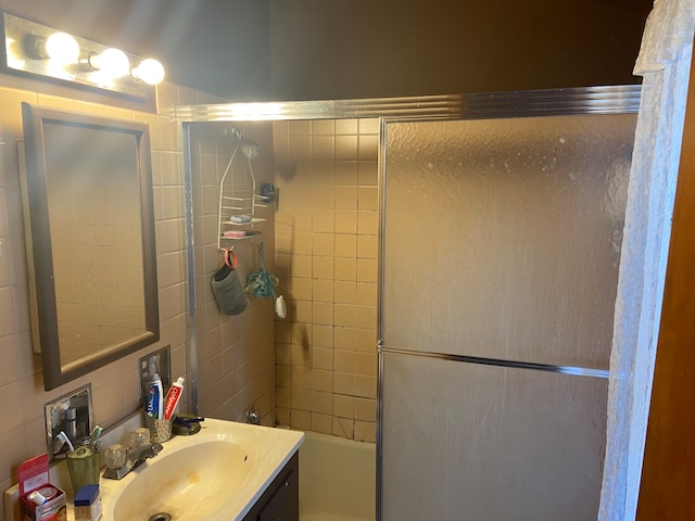 bathroom featuring backsplash, combined bath / shower with glass door, and vanity