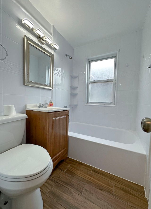 full bathroom with vanity, tile walls, toilet, hardwood / wood-style flooring, and tiled shower / bath combo