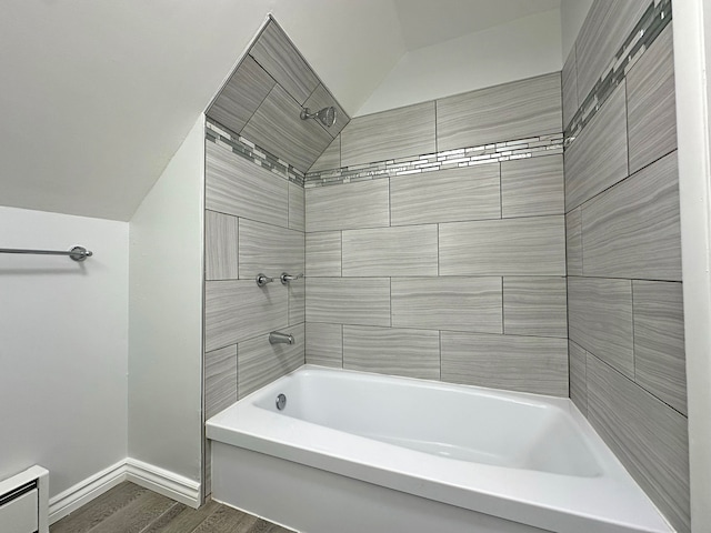 bathroom featuring lofted ceiling, tiled shower / bath, hardwood / wood-style flooring, and a baseboard radiator