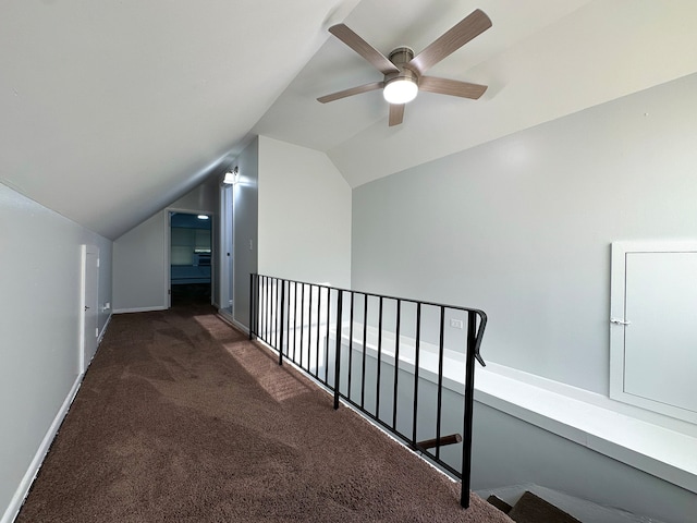 corridor featuring lofted ceiling and dark carpet