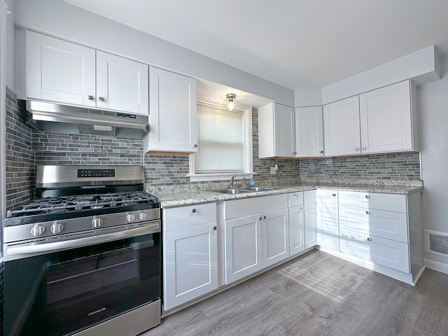 kitchen featuring stainless steel gas range, sink, decorative backsplash, white cabinetry, and light wood-type flooring