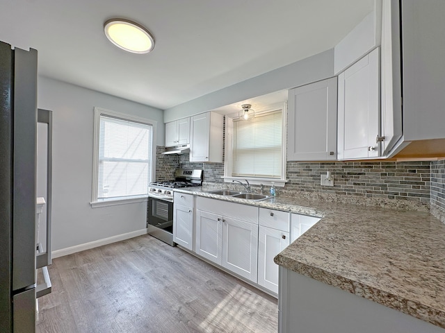 kitchen featuring light hardwood / wood-style flooring, stainless steel gas range oven, sink, decorative backsplash, and white cabinets