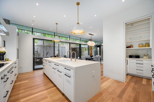 kitchen featuring a kitchen island with sink, white cabinetry, a wealth of natural light, and sink