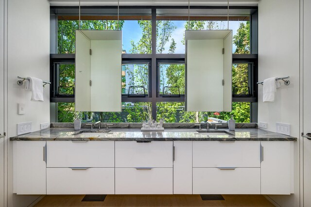 kitchen with white cabinets, dark stone counters, and sink