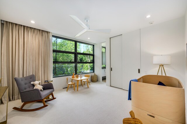 living area with light colored carpet and ceiling fan