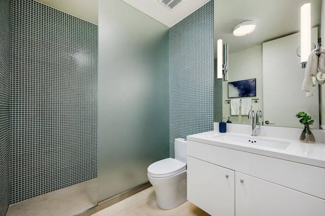 bathroom with vanity, toilet, and a tile shower