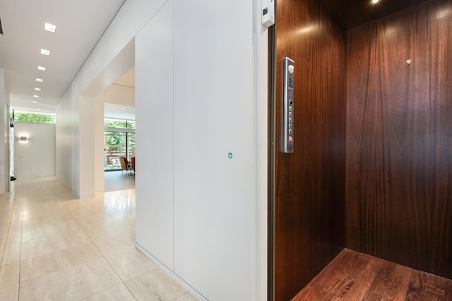 corridor featuring elevator and light tile patterned flooring