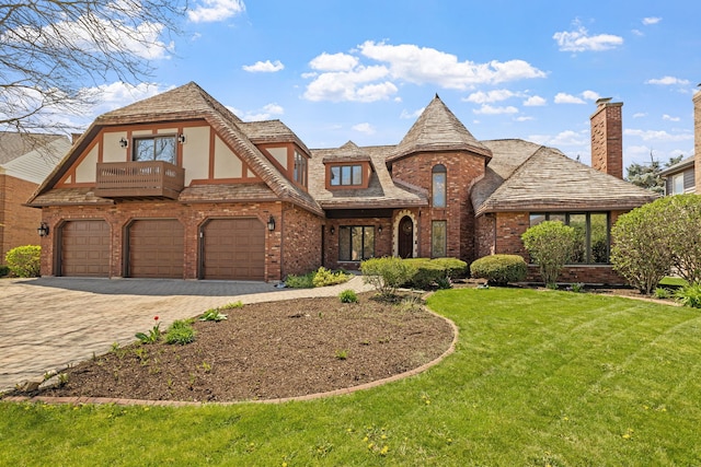 view of front facade with an attached garage, brick siding, a front yard, decorative driveway, and a balcony