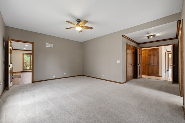 empty room with visible vents, carpet flooring, baseboards, and ceiling fan