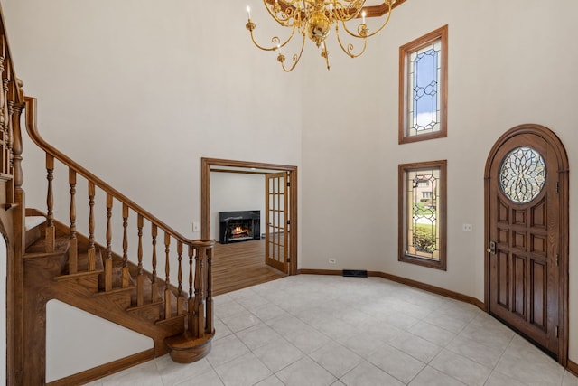3944 Paradise Canyon Ct, Naperville, IL 60564 - foyer featuring stairs, a towering ceiling, a lit fireplace, a chandelier, and light tile patterned floors