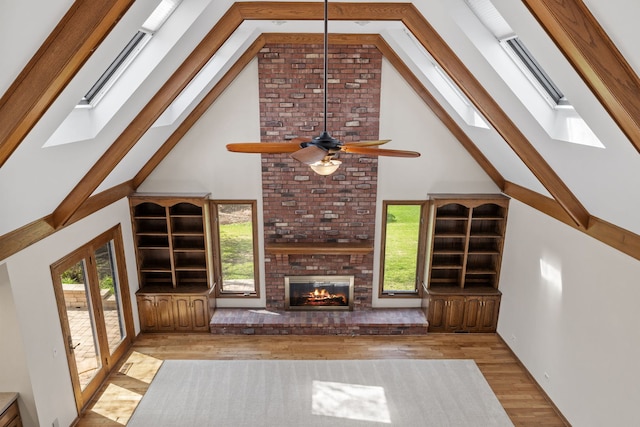 3944 Paradise Canyon Ct, Naperville, IL 60564 - unfurnished living room featuring ceiling fan, a skylight, a fireplace, wood finished floors, and high vaulted ceiling