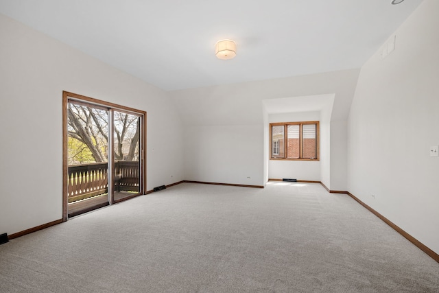 empty room featuring baseboards, vaulted ceiling, visible vents, and light carpet