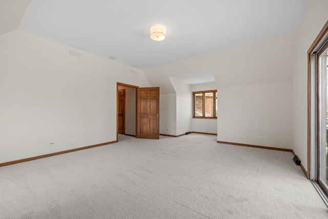 unfurnished bedroom with visible vents, baseboards, vaulted ceiling, and light colored carpet