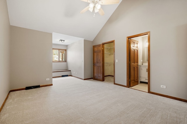 unfurnished bedroom with a walk in closet, baseboards, light carpet, and visible vents