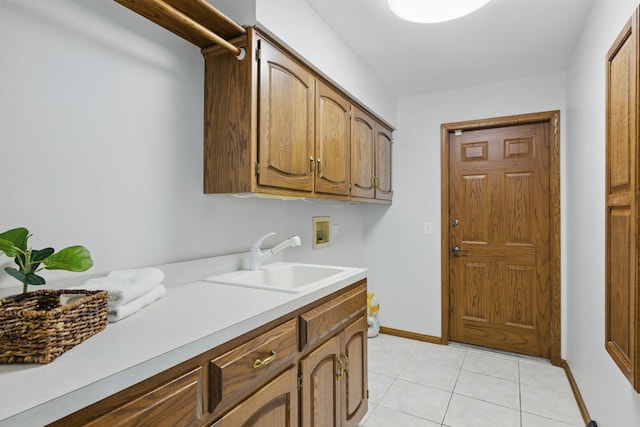 washroom with cabinet space, light tile patterned flooring, a sink, hookup for a washing machine, and baseboards