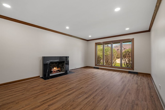 unfurnished living room featuring a fireplace with flush hearth, baseboards, ornamental molding, and wood finished floors