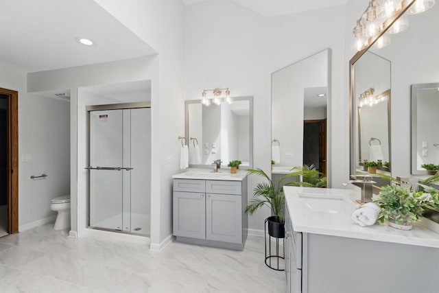 bathroom featuring two vanities, toilet, a shower stall, and a sink