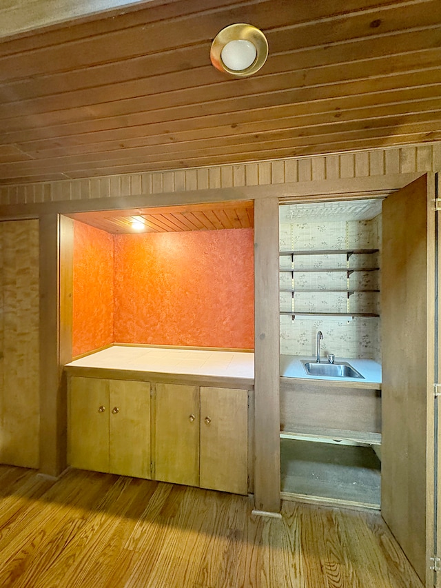 bar with light wood-type flooring, wood ceiling, and a sink