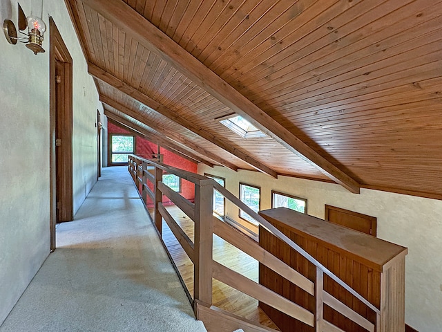 hallway with wooden ceiling, vaulted ceiling with skylight, and a textured wall