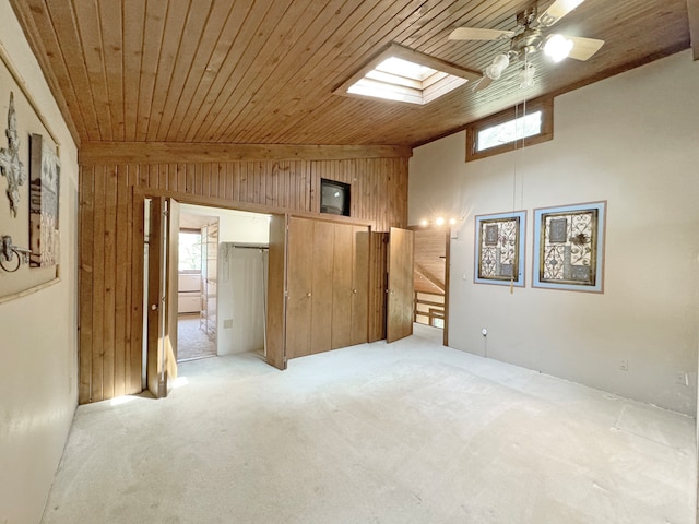 unfurnished bedroom with light carpet, multiple windows, ceiling fan, and wooden walls