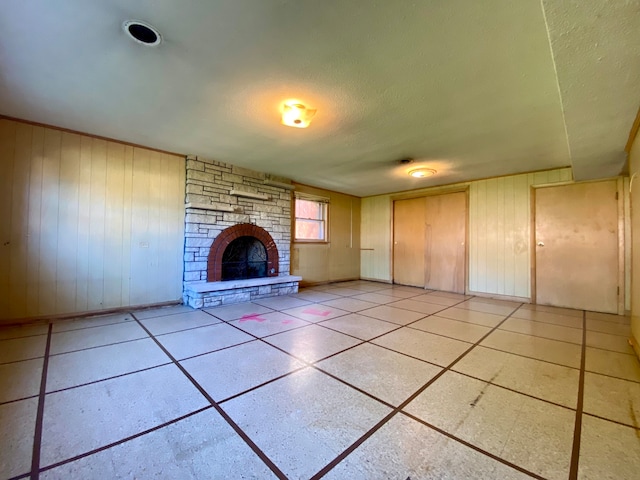 unfurnished living room with a textured ceiling and a stone fireplace