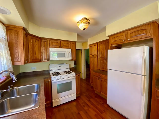 kitchen featuring dark wood-type flooring, white appliances, and sink