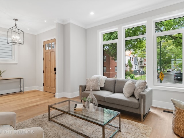 living room featuring an inviting chandelier, light hardwood / wood-style floors, and ornamental molding