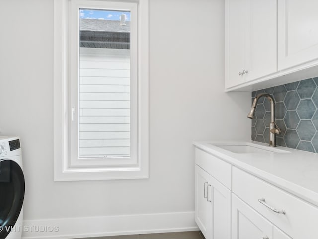 washroom featuring cabinets, sink, and washer / clothes dryer