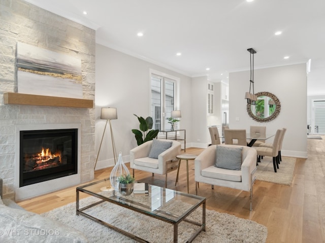 living room with a fireplace, light hardwood / wood-style floors, and ornamental molding