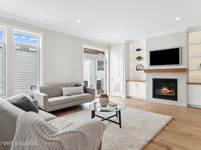 living room with a fireplace, ornamental molding, and light hardwood / wood-style floors