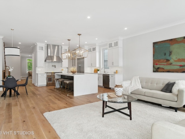 living room with ornamental molding, an inviting chandelier, and light wood-type flooring