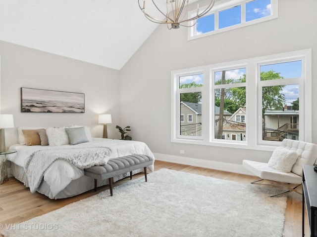 bedroom with light wood-type flooring, high vaulted ceiling, and an inviting chandelier