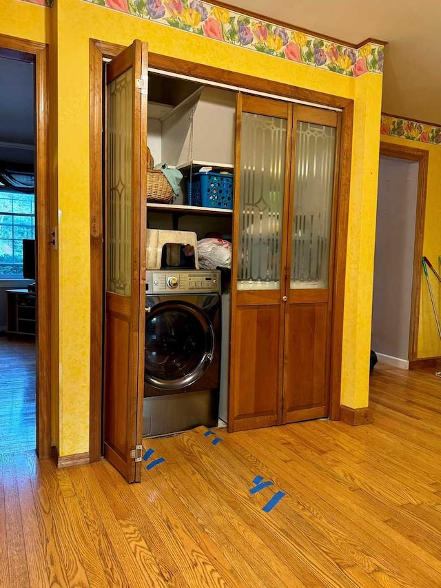 clothes washing area with light hardwood / wood-style flooring and washer / dryer