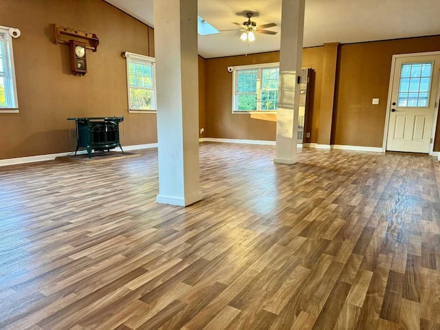 unfurnished living room with hardwood / wood-style floors, ceiling fan, a wood stove, and a wealth of natural light