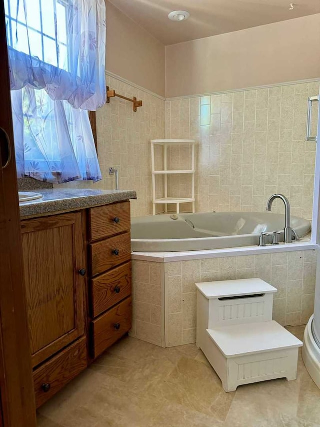 bathroom with tile walls, tile patterned floors, tiled bath, and vanity