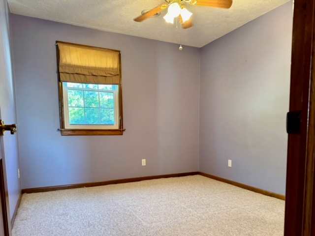 carpeted empty room with ceiling fan and a textured ceiling